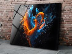 an abstract painting is displayed in front of a brick wall