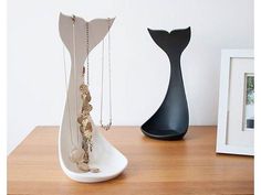 a white vase sitting on top of a wooden table next to a black and white sculpture