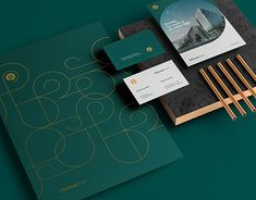 an assortment of business cards and stationery items on a green surface with gold accents