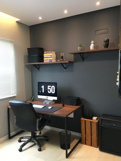 a desk with a computer on top of it in front of a wall mounted speaker