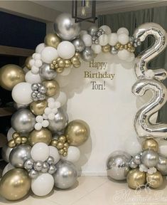 a happy birthday balloon arch with silver, gold and white balloons in the shape of numbers