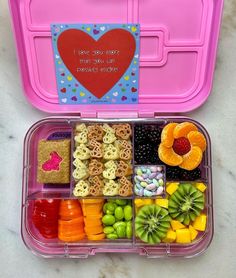 a pink lunch box filled with lots of different types of fruit and veggies