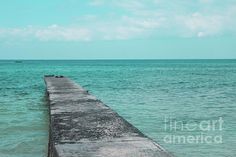 a long pier stretching out into the ocean with two boats in the water behind it