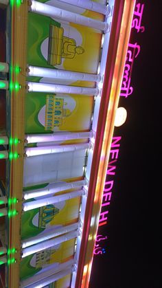 a carnival ride with neon lights and signs on the side of it at night time