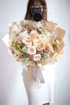 a woman holding a bouquet of flowers with a camera in her hand while she takes a photo