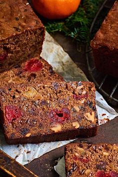 slices of fruitcake sitting on top of paper next to an orange