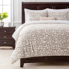 a bed with a leopard print comforter and two nightstands in front of it