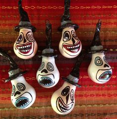 six light bulbs with painted faces on them are hanging from the side of a rug