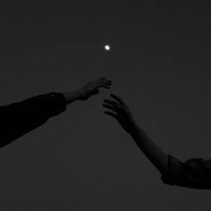 two people reaching out towards each other in the night sky, with one person reaching for the moon