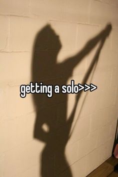 the shadow of a person holding an object in front of a brick wall that says getting a solo