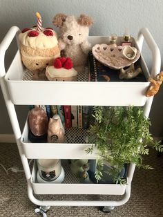 two teddy bears sitting on top of a white cart filled with books and other items