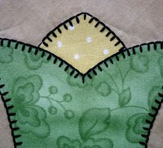 an embroidered piece of cloth with green and yellow flowers on it