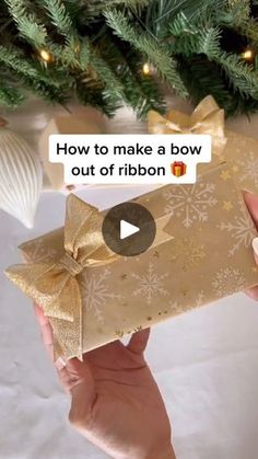 someone holding up a gift under a christmas tree with the caption how to make a bow out of ribbon