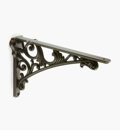 an ornate iron shelf bracket on a white wall