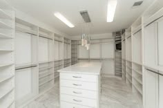 an empty walk in closet with white cabinets