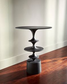 a black table sitting on top of a wooden floor next to a white wall and window