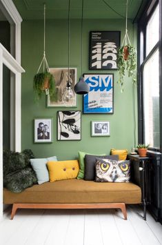 a living room with green walls and pictures on the wall, including an orange couch