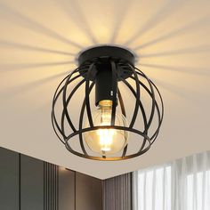 a light that is hanging from the ceiling in a room with white walls and curtains