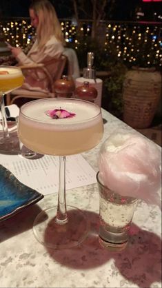 two drinks sitting on top of a table next to each other in front of a woman