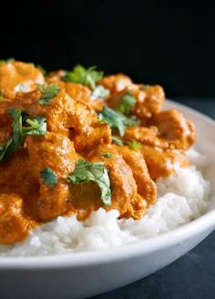 a white bowl filled with rice covered in meat and garnished with cilantro