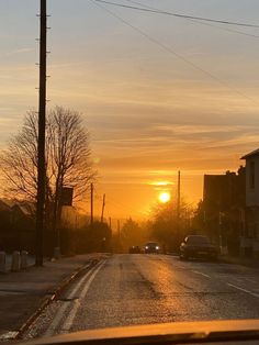 the sun is setting over an empty street