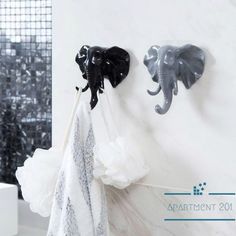 two black and white elephant hooks on the wall next to a towel rack in a bathroom