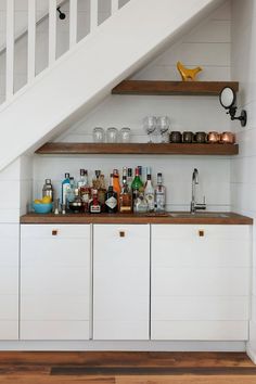 an under the stairs bar with liquor bottles and glasses on it's counter top