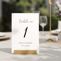 a table number is placed on top of a place card holder at a wedding reception