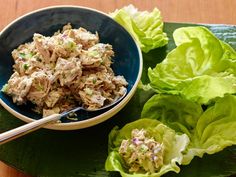 a bowl filled with salad next to lettuce leaves