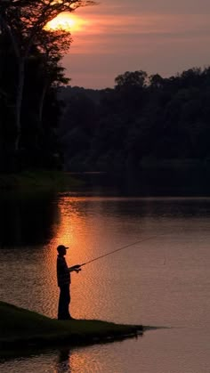 a man standing on the edge of a lake while fishing