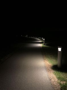 the path is lit up at night with several lights on it and grass in the foreground