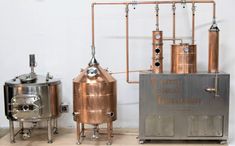 two large metal tanks sitting next to each other on top of a wooden floor in front of a white wall