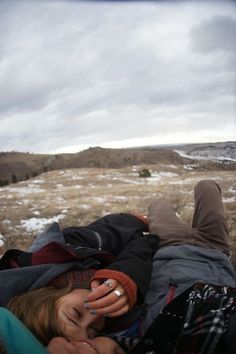 two people laying on the ground with their arms around each other while one person covers his face