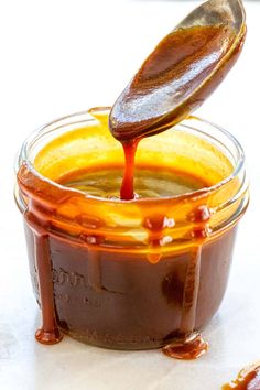 a spoon pouring caramel sauce into a jar