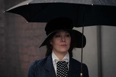 a woman wearing a suit and tie holding an umbrella