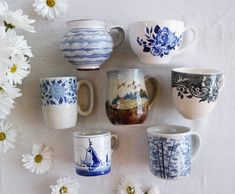 there are many cups that have been placed on the table with daisies around them