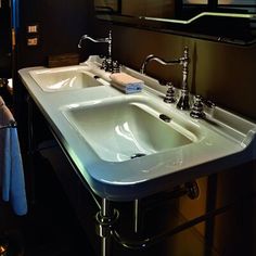 a bathroom sink sitting under a mirror next to a towel dispenser on a rack