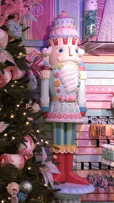 a christmas tree in front of a store window with decorations on it and a large wooden nutcracker