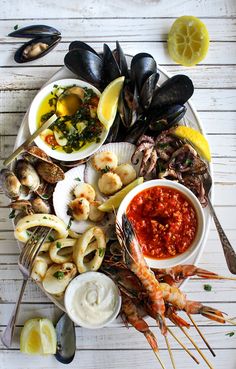 a plate full of seafood and clams on top of a white wooden table with the caption's name above it