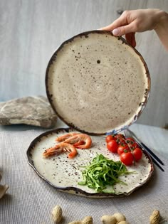 a plate with shrimp, tomatoes and lettuce on it next to some peanuts