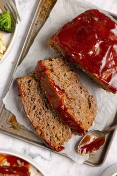 two slices of meatloaf with ketchup and broccoli on the side