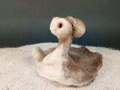 a stuffed animal sitting on top of a pile of white sand next to a gray wall