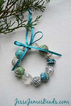 a christmas ornament hanging from a tree branch with blue ribbon and beads on it