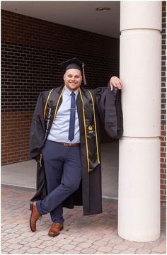 a man in a graduation gown leaning against a column