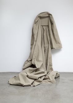 a large piece of cloth sitting on top of a cement floor next to a white wall