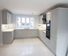 an empty kitchen with white tile floors and cabinets in the center, along with large windows