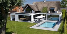 an aerial view of a house with a pool in the foreground and lawn area