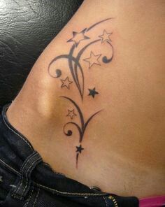 a woman's stomach with stars and swirls tattoo on her side ribcage