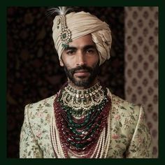 a man in a turban and jewelry looks at the camera