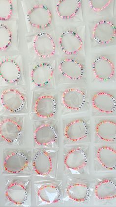 many different bracelets in plastic bags on a white surface with words that spell out the word